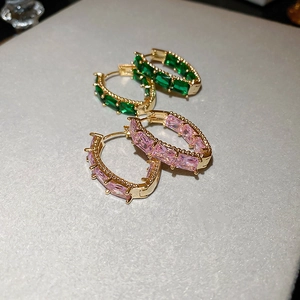 Close-up of gold hoop earrings with rectangular green and pink cubic zirconia stones