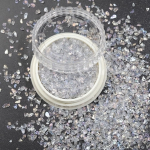 Macro shot of iridescent glass gravel in transparent jar for DIY nail art and crafts