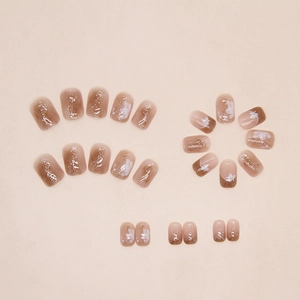 Detail of gradient brown and nude press-on nails with white flower patterns and fine glitter