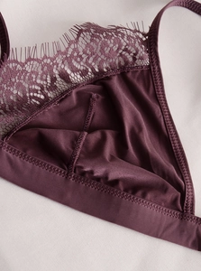 Dettaglio macro del pizzo bordeaux e del tessuto satinato sulla coppa del reggiseno a triangolo