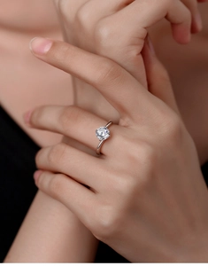 Detailed close-up of a classic four-prong moissanite ring on a finger in silver finish