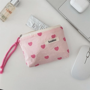 Detailed view of pink canvas cosmetic bag with red heart pattern and zip puller