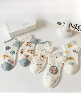 Close-up of five pairs of white cotton socks with cute bear patterns and ribbed cuffs