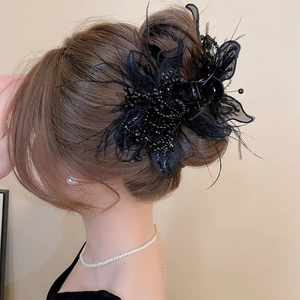 Detailed view of elegant black butterfly hair claw with feathers and beads on model's hair