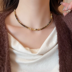 Close-up of vintage tiger eye stone and gold bead necklace on model's neck
