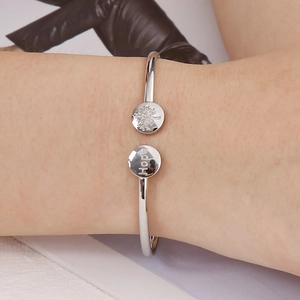 Polished silver Hope tree of life open cuff bracelet worn on a female wrist over a magazine