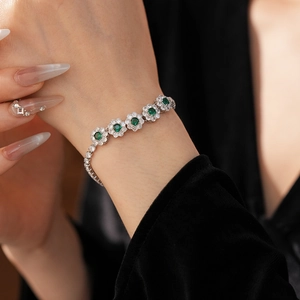 Détail d'un bracelet floral serti de zircons verts porté avec une élégance raffinée