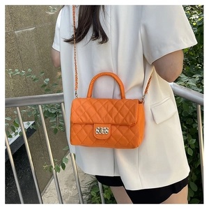Outdoor shot of bright orange quilted crossbody bag with gold chain and metal lock
