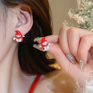 Close-up of a cute Christmas snowman earring with red hat worn by a model