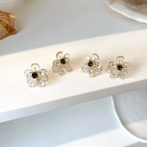 Detailed macro of four crystal floral hair claws with black beads on a minimalist stand