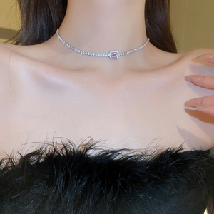 Close-up of a silver choker necklace with a pink square zircon stone on a model's neck
