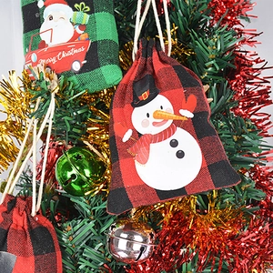 Christmas red and green plaid drawstring gift bags hanging on a festive Xmas tree