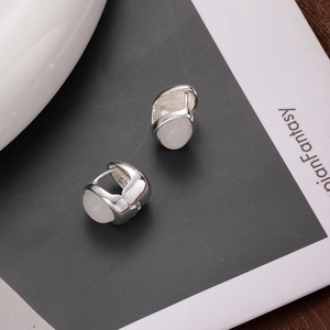 Elegant silver earrings with white teardrop cat's eye stone on a minimalist background