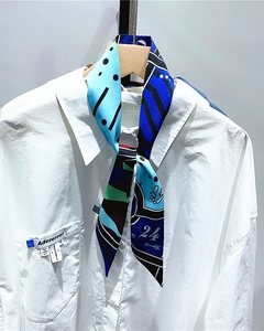 Detail of colorful twilly scarf with blue and green geometric prints tied on shirt collar