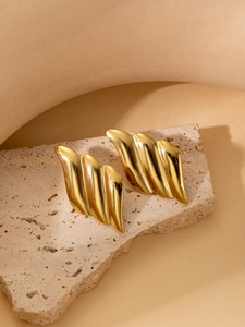 Detailed view of 18K gold plated titanium wavy earrings on a textured stone surface