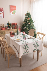 Detailed view of Christmas tablecloth with holly berry patterns and decorative tassels