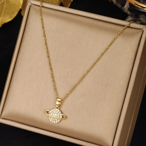 Close-up of golden Saturn pendant with sparkling cubic zirconia on luxury jewelry box