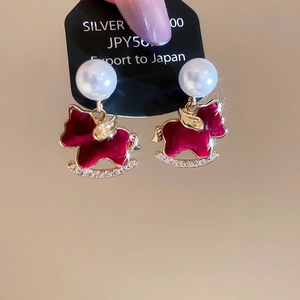 Macro detail of red enamel horse earrings with pearls and crystals in gold finish