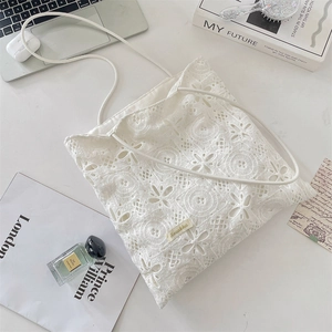 Close-up of white floral embroidery lace tote bag with brand label on a flat lay desk