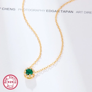 Detail of 925 silver gold plated necklace with emerald green zircon pendant macro view