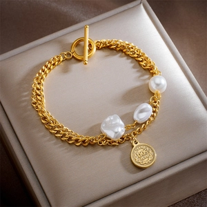 Elegant double-layered gold chain bracelet with white pearls and a vintage coin pendant