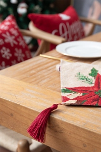 Detail of Christmas snowman table runner with red poinsettia pattern and tassel on wood table