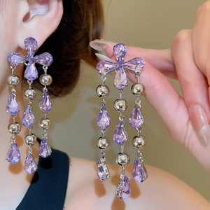 Detailed close-up of lilac crystal teardrop tassel earrings with silver clover design