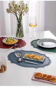 Detailed view of irregular leather placemats in red, green, blue and pink on a dining table