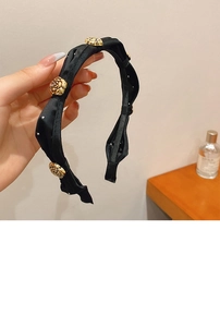 Detailed close-up of golden metallic rose charms on a black satin headband with non-slip teeth