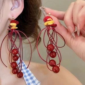 Makroaufnahme langer roter Quastenohrringe mit Muschelscheiben und Harzperlen