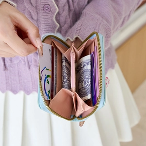 Short bow-tie wallet with pompom charm featuring multi-slot accordion interior design