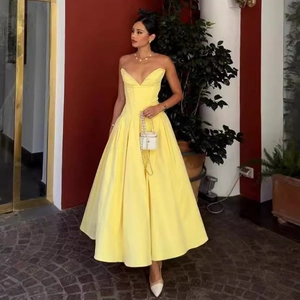 Detail of elegant yellow satin strapless gown with corset waist and full A-line skirt