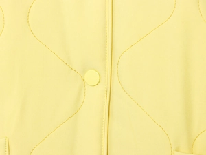 Detail of bright yellow quilted jacket featuring wavy patterns and matching resin buttons