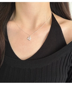 Detail of s925 silver star necklace with pink zircon on model's neck
