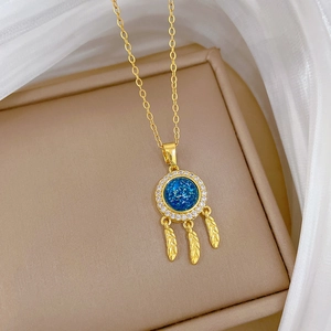 Luxurious gold dreamcatcher necklace with blue gemstone and feathers on beige box