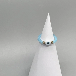 Detail of light blue beaded elastic ring featuring a central white Evil Eye charm bead