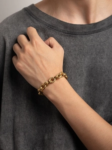 Close-up of a gold-toned vintage woven chain bracelet worn on a wrist for men