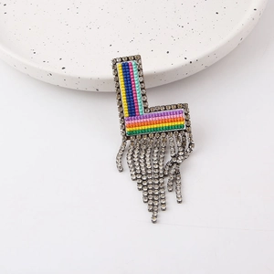 Detail of L-shaped brooch with colorful woven stripes and sparkling rhinestone tassels
