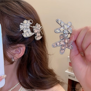 Macro detail of rhinestone-studded star and bow hair clips with silver-tone alloy base