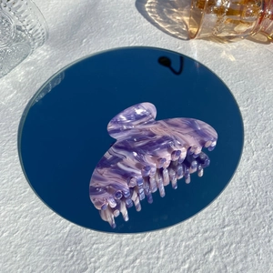 Detailed view of large purple marbled acetate hair claw clip on a mirror base