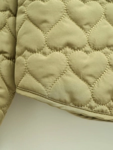 Macro view of olive green heart-shaped quilted fabric with precise stitching details