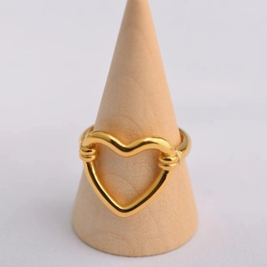 Vue macro d'une bague coeur dorée sur support en bois avec fond blanc épuré