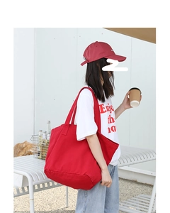 Outdoor shot of a model wearing a large red canvas tote bag with a white casual t-shirt