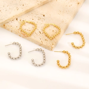 Detailed view of mixed gold and silver beaded hoop earrings on a marble surface