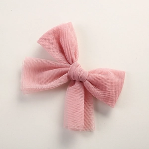 Close-up of pink tulle bow hair clip showing soft mesh texture and delicate design