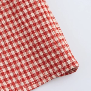 Close-up of red and white checkered fabric with detailed stitching and cotton texture