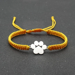 Detail of yellow braided rope bracelet with a polished silver paw print charm