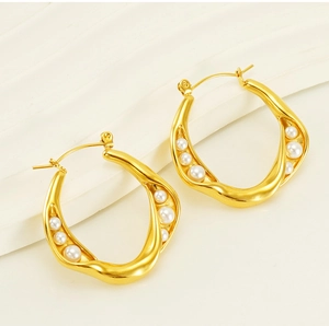 Macro shot of gold-plated geometric wave hoop earrings with white pearl insets