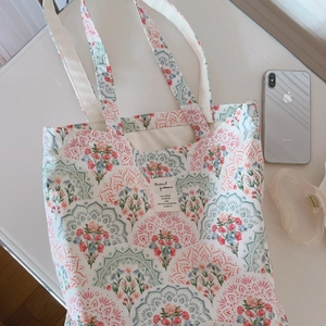Floral cotton canvas tote bag with mandala print and rectangular label on white desk
