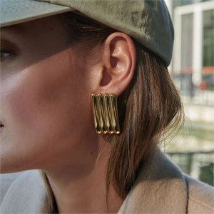 Polished gold rectangular earrings with vertical ribbed texture on a fashion model